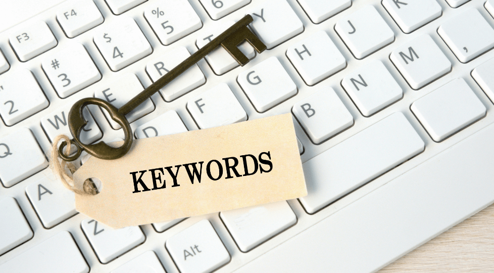 白いキーボードの上に「KEYWORDS」と書かれたタグ付きの鍵が置かれている写真。